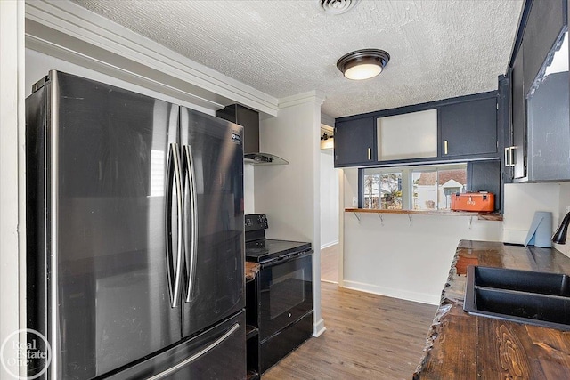 kitchen featuring black electric range oven, wall chimney exhaust hood, sink, stainless steel fridge, and dark hardwood / wood-style flooring