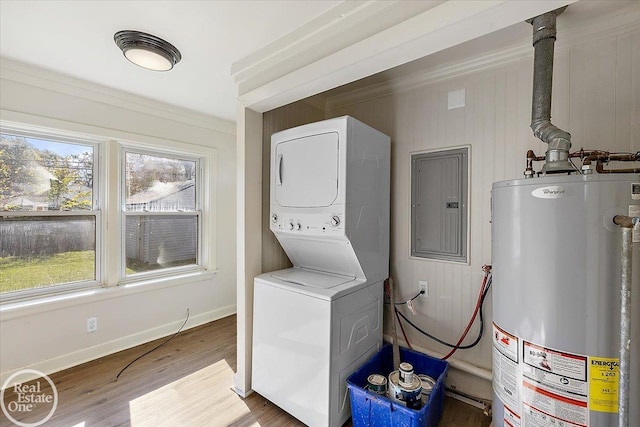 washroom featuring stacked washer / drying machine, water heater, light hardwood / wood-style flooring, ornamental molding, and electric panel