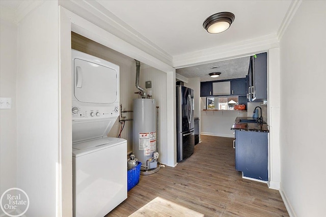 laundry room with crown molding, sink, water heater, dark wood-type flooring, and stacked washer / drying machine