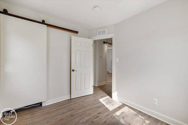 empty room with a barn door and wood-type flooring