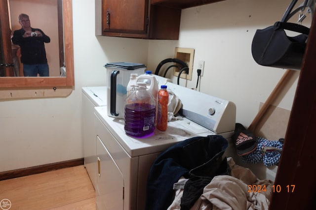 laundry area with light hardwood / wood-style flooring, separate washer and dryer, and cabinets