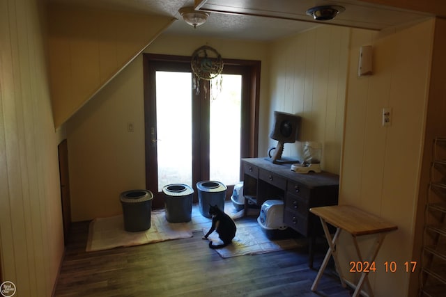 interior space with dark wood-type flooring, wood walls, and a textured ceiling