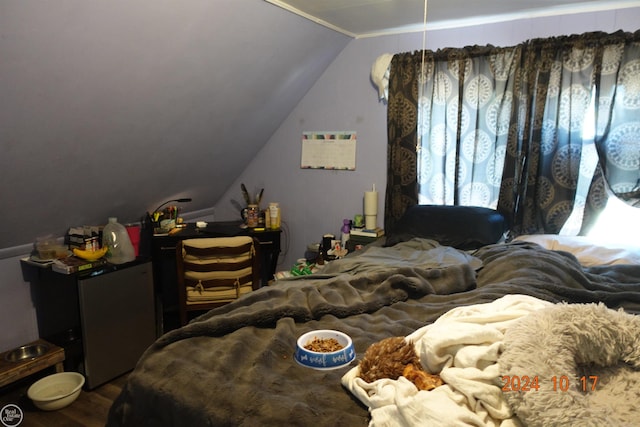 bedroom with lofted ceiling, hardwood / wood-style flooring, and stainless steel refrigerator