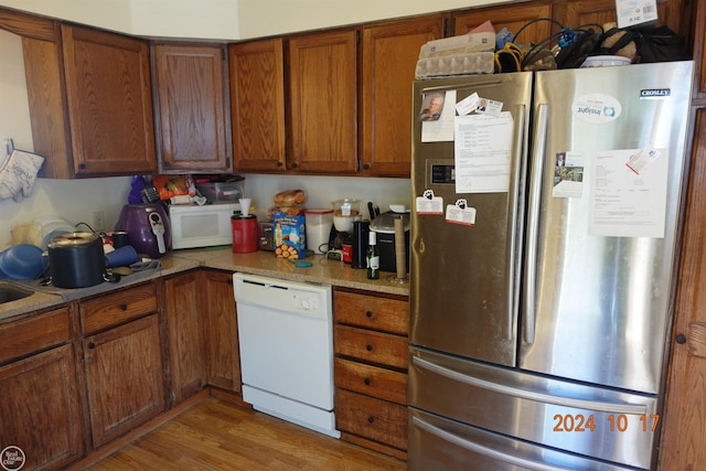 kitchen with hardwood / wood-style floors, light stone countertops, and white appliances