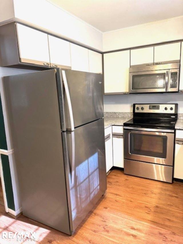 kitchen with white cabinetry, stainless steel appliances, and light wood-type flooring