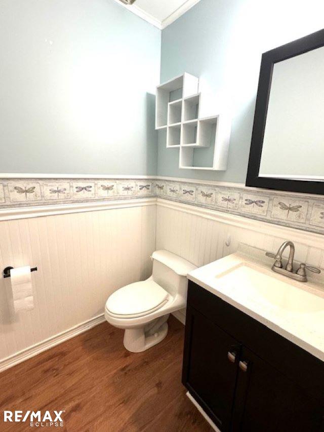 bathroom featuring vanity, toilet, wood-type flooring, and ornamental molding