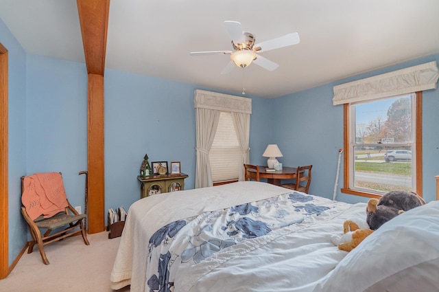 bedroom featuring ceiling fan, beamed ceiling, and light colored carpet