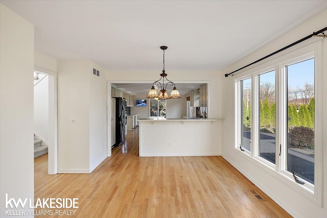 unfurnished dining area with light wood-type flooring and a chandelier