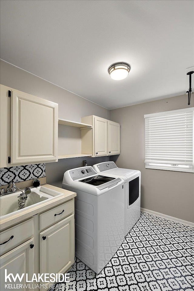 washroom with cabinets, sink, and washing machine and clothes dryer