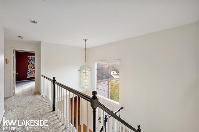 hallway with an inviting chandelier and carpet floors