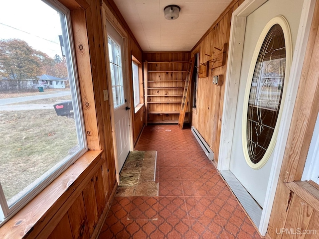 interior space with a baseboard heating unit and wooden walls