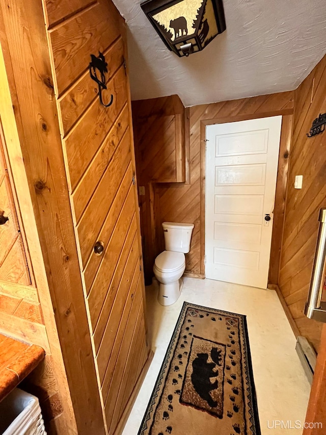 bathroom with toilet and wooden walls