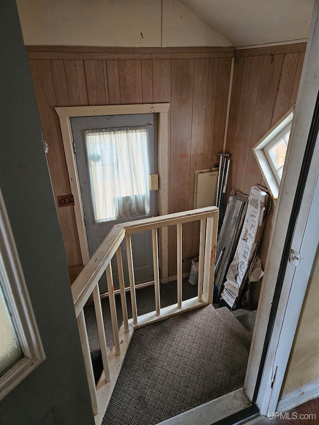 stairs featuring wood walls and vaulted ceiling