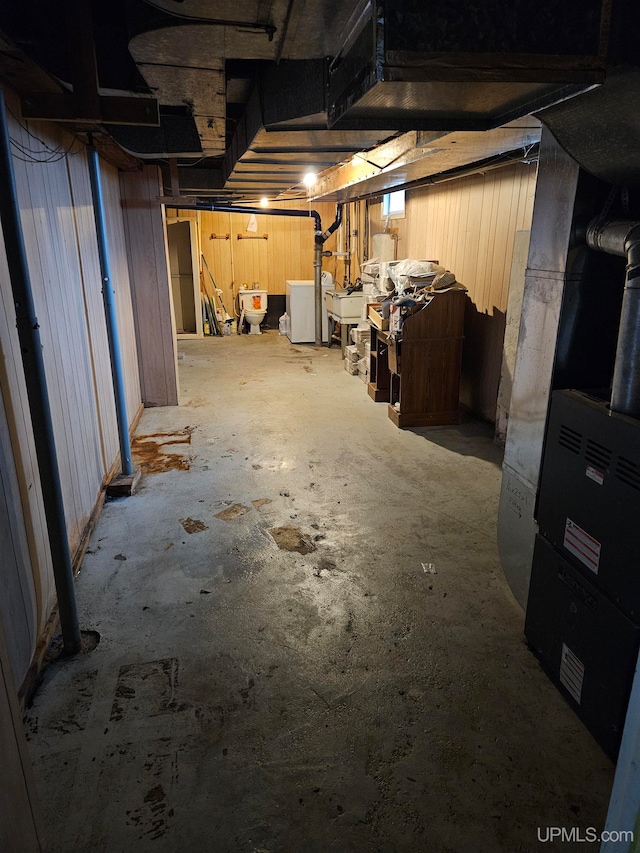 basement featuring sink, washer and clothes dryer, and heating unit