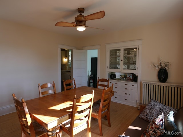 dining area with light hardwood / wood-style flooring, radiator heating unit, and ceiling fan