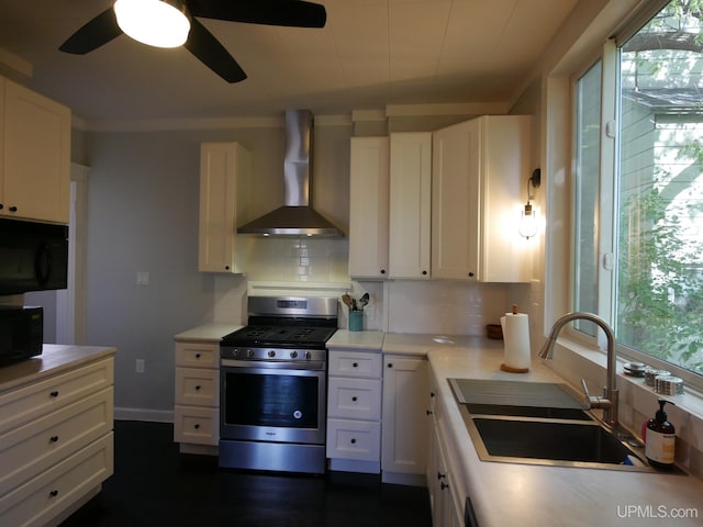 kitchen with tasteful backsplash, sink, white cabinetry, wall chimney exhaust hood, and stainless steel gas range oven