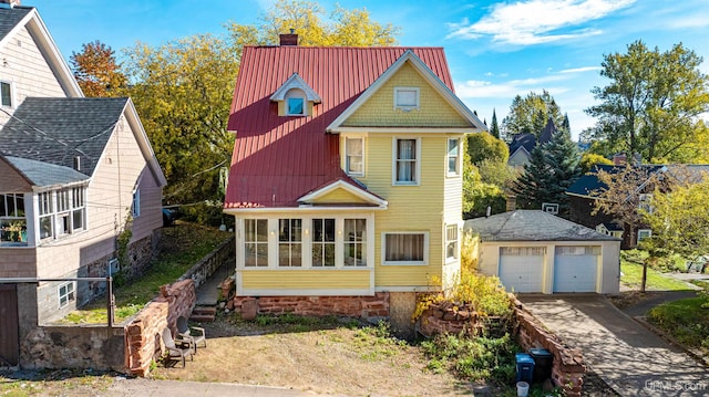 view of front of home featuring an outbuilding, a garage, and a sunroom