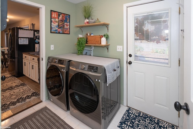 laundry area with washing machine and clothes dryer and light tile patterned floors