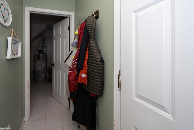 corridor with strapped water heater and light tile patterned floors