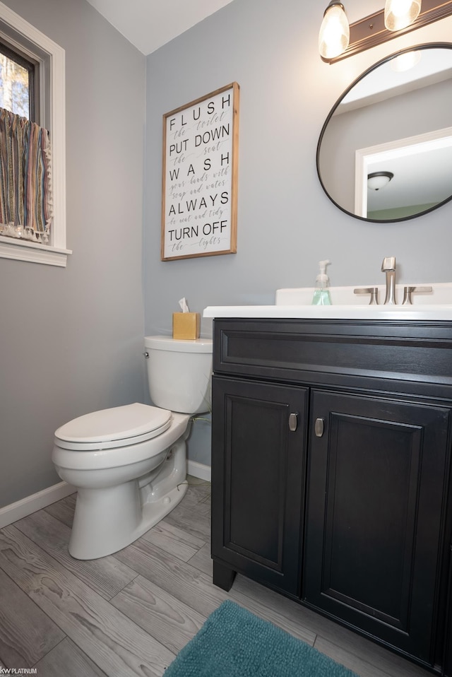 bathroom featuring toilet, vanity, and hardwood / wood-style floors