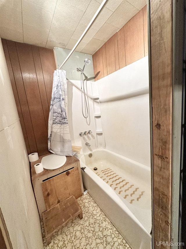 bathroom featuring shower / tub combo and wooden walls