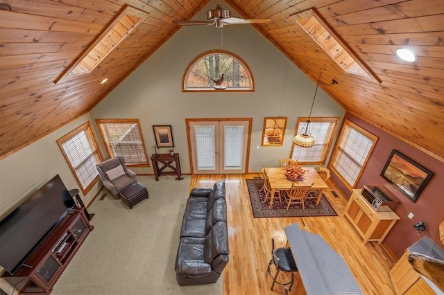 living room featuring a skylight, ceiling fan, wooden ceiling, high vaulted ceiling, and light hardwood / wood-style flooring