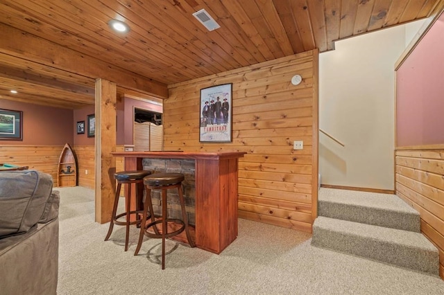 bar featuring wood walls, light colored carpet, and wooden ceiling