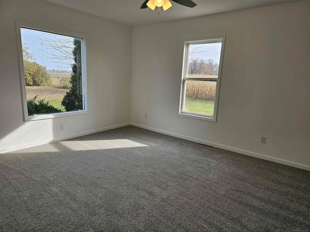 empty room with ceiling fan and dark colored carpet