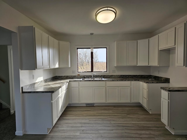 kitchen featuring hardwood / wood-style floors, sink, white cabinets, and pendant lighting