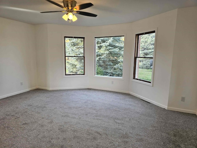 spare room with ceiling fan and dark colored carpet