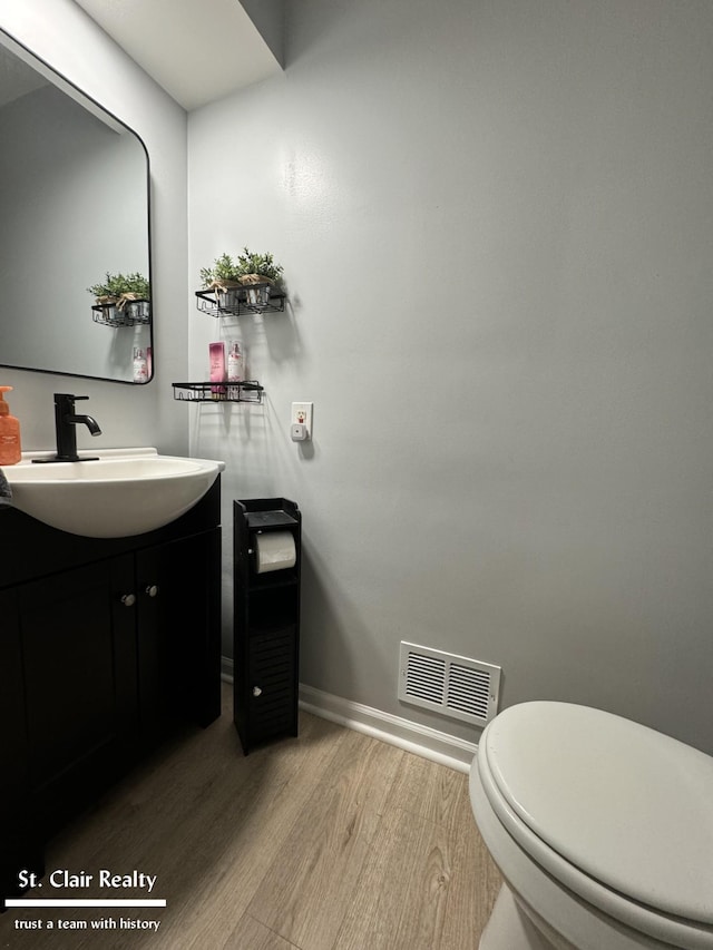 bathroom with hardwood / wood-style floors, vanity, and toilet