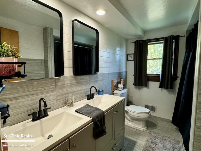 bathroom with vanity, toilet, decorative backsplash, and tile walls