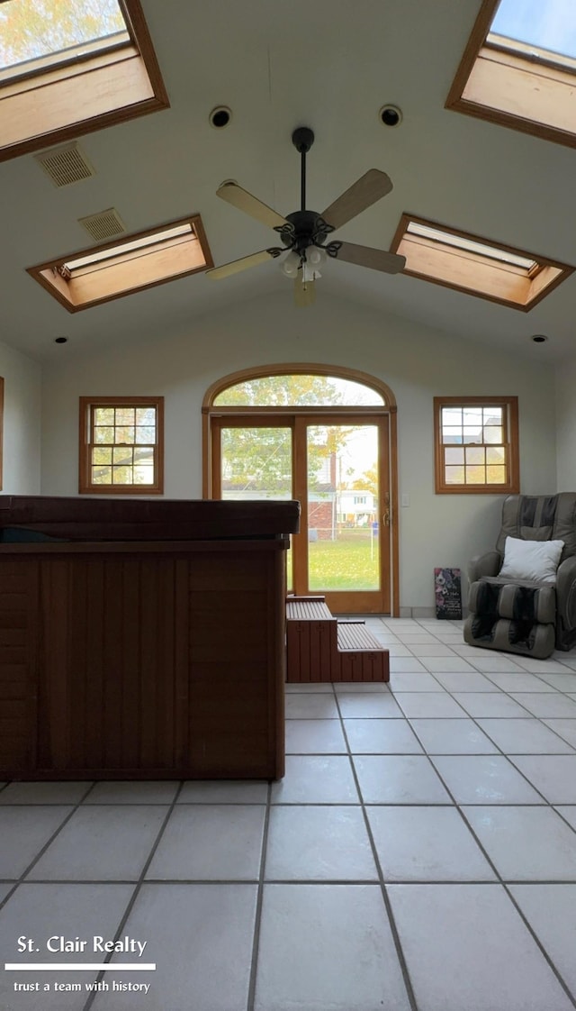 interior space featuring lofted ceiling with skylight, light tile patterned floors, and ceiling fan