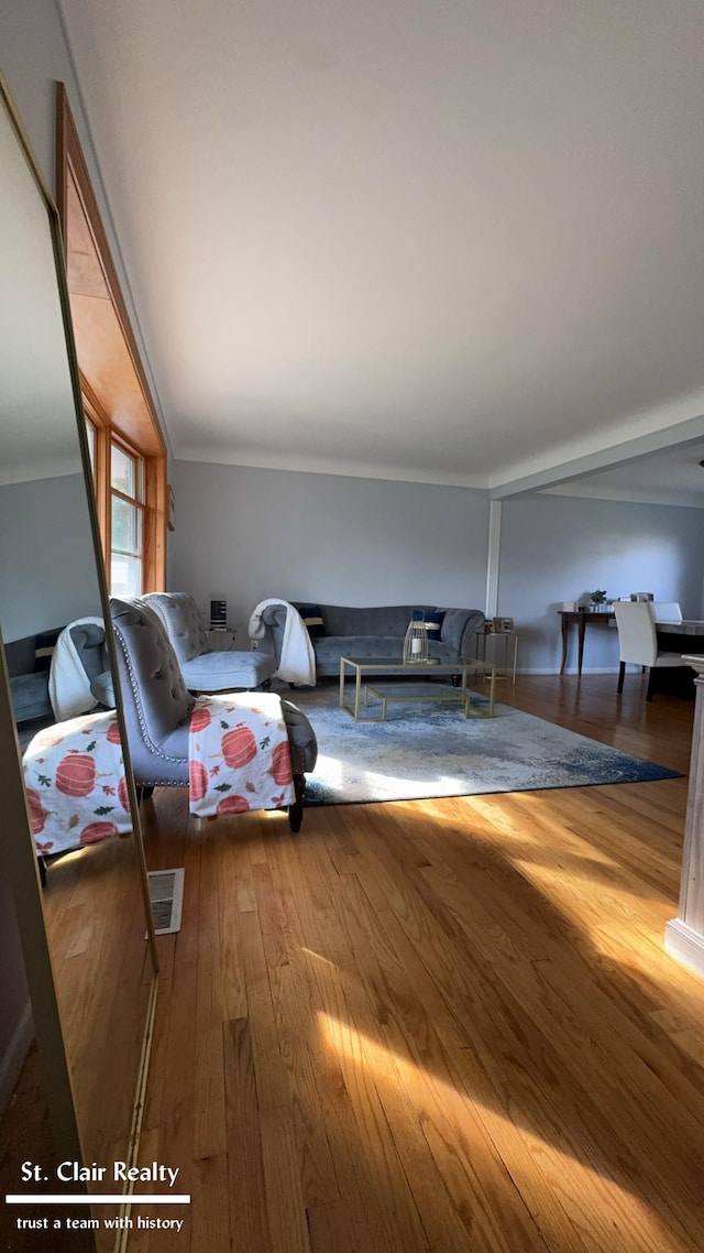 living room featuring hardwood / wood-style flooring, lofted ceiling, and crown molding