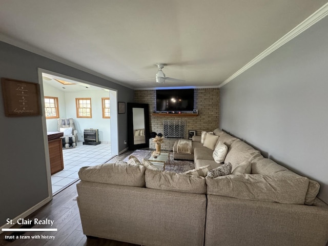 living room featuring a brick fireplace, ceiling fan, light hardwood / wood-style flooring, and ornamental molding