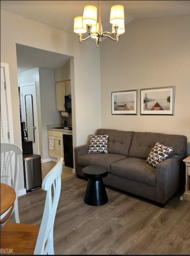 living room with an inviting chandelier, hardwood / wood-style flooring, and lofted ceiling