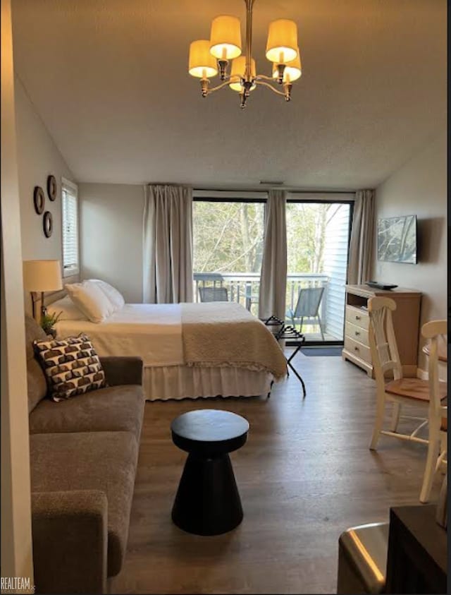 bedroom with hardwood / wood-style floors, a chandelier, and access to outside