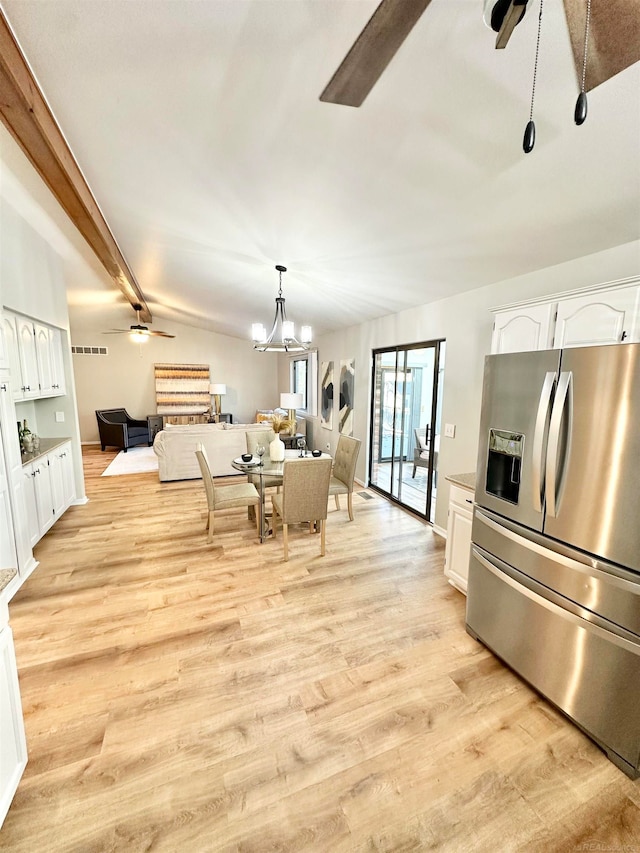 kitchen featuring ceiling fan with notable chandelier, light wood-type flooring, white cabinets, stainless steel fridge, and pendant lighting