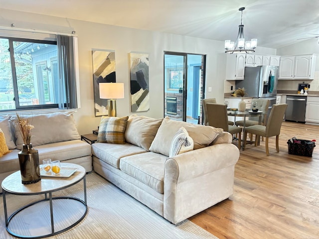 living room with ceiling fan with notable chandelier and light hardwood / wood-style flooring