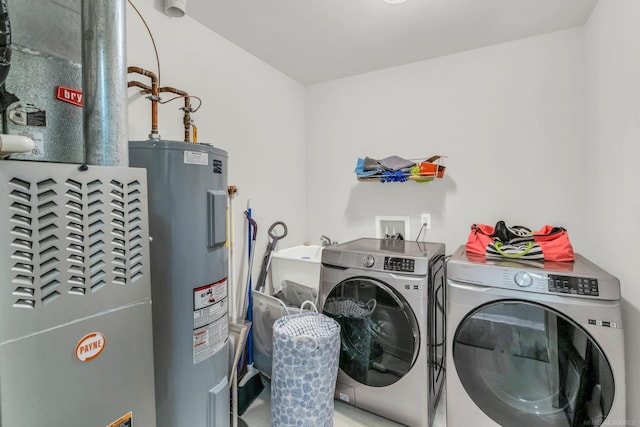 laundry area with electric water heater, heating unit, and washing machine and clothes dryer