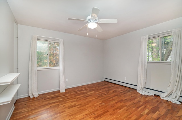 spare room featuring a baseboard heating unit, light wood-type flooring, and ceiling fan