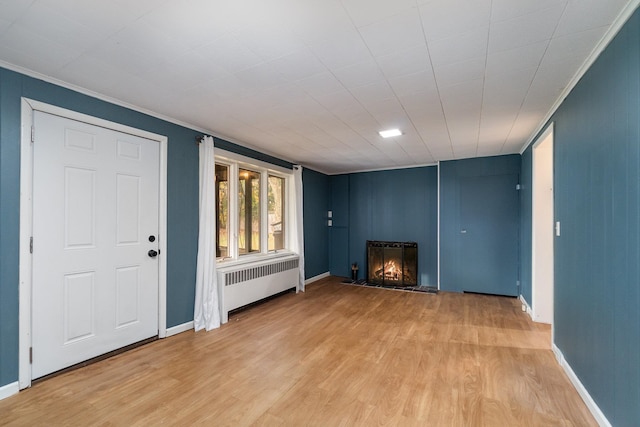 unfurnished living room featuring radiator, ornamental molding, and light hardwood / wood-style flooring