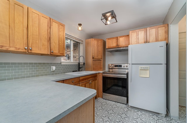 kitchen featuring white fridge, tasteful backsplash, sink, and stainless steel range with electric cooktop