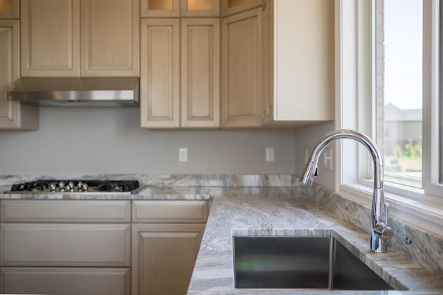 kitchen featuring light stone counters, sink, and stainless steel gas stovetop