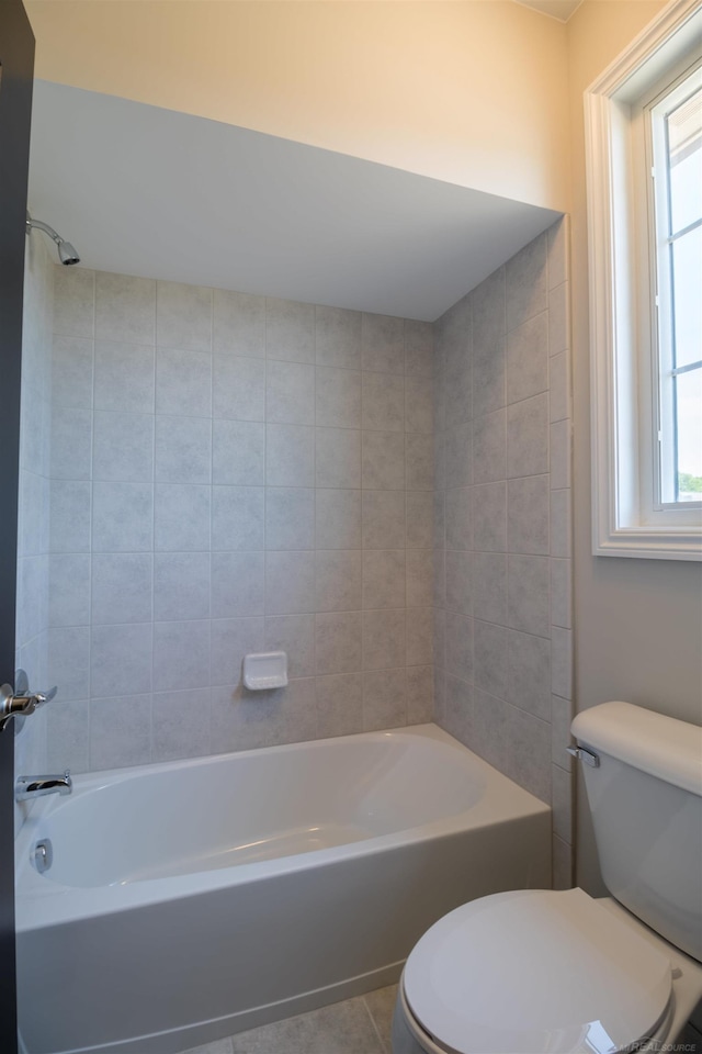 bathroom featuring toilet, tile patterned floors, and tiled shower / bath