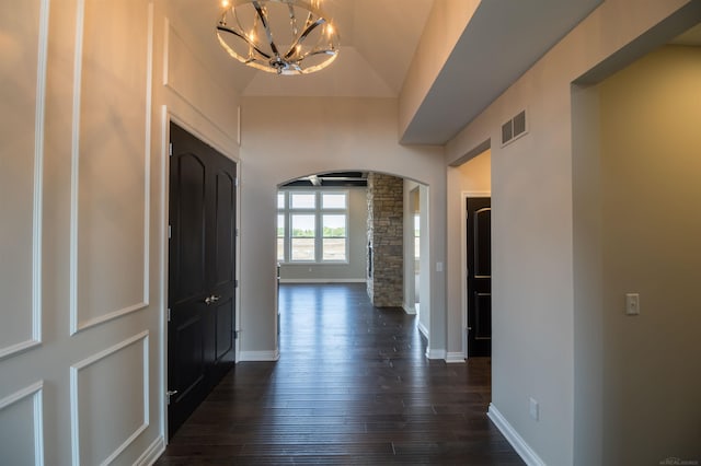 corridor featuring a chandelier, vaulted ceiling, and dark hardwood / wood-style flooring