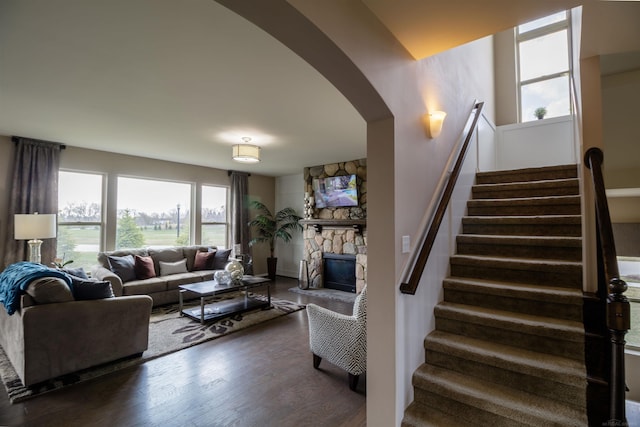 living room with a stone fireplace and dark hardwood / wood-style flooring