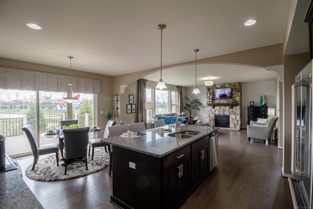 kitchen with sink, light stone counters, dark brown cabinets, and dark hardwood / wood-style flooring