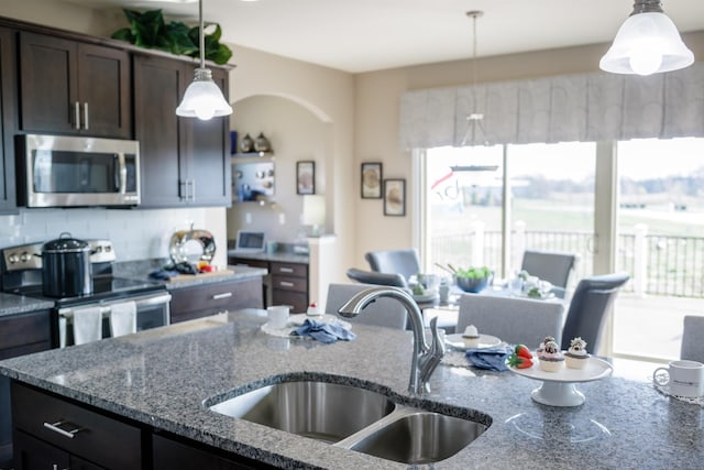 kitchen featuring decorative backsplash, stone counters, sink, dark brown cabinetry, and stainless steel appliances