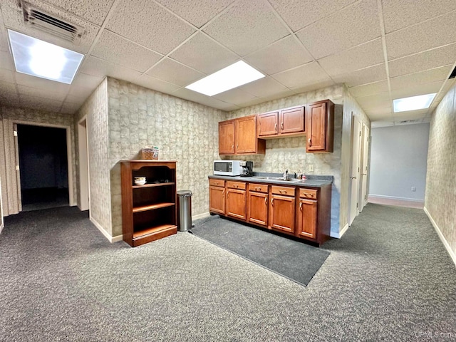 kitchen featuring a paneled ceiling, sink, and dark carpet